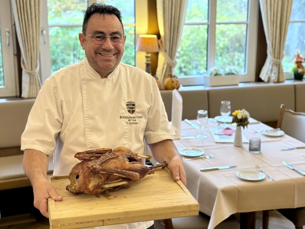 Georg Echtler präsentiert einen Gänsebraten auf einem Holzbrett im Bonsmannshof